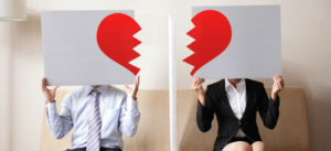 couple hiding their faces in a broken heart signs