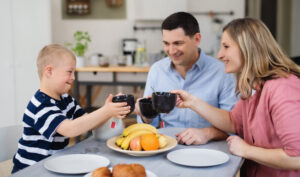 Happy family with down syndrome son at the table, having breakfast.